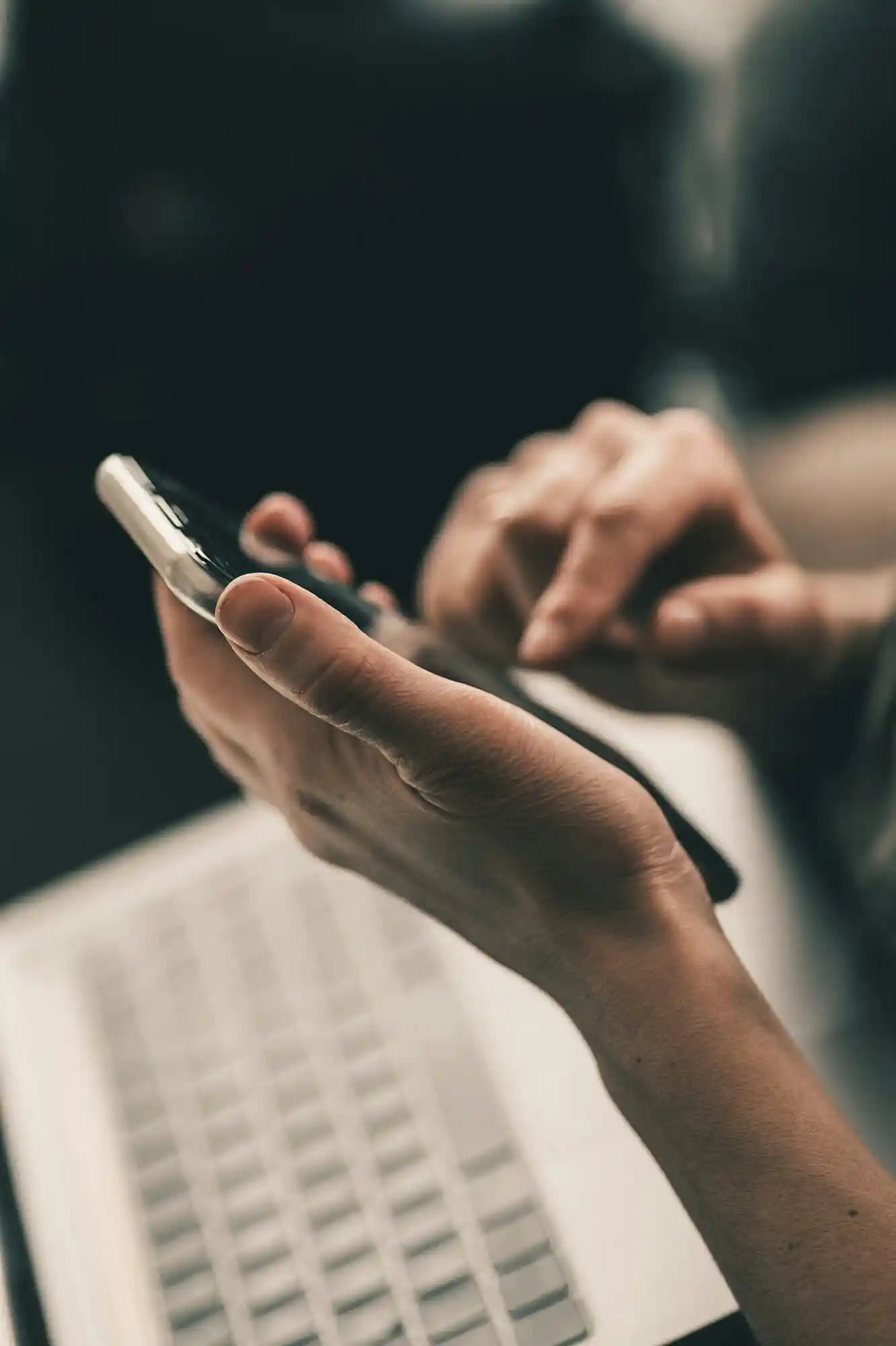 Hands typing on a phone and laptop